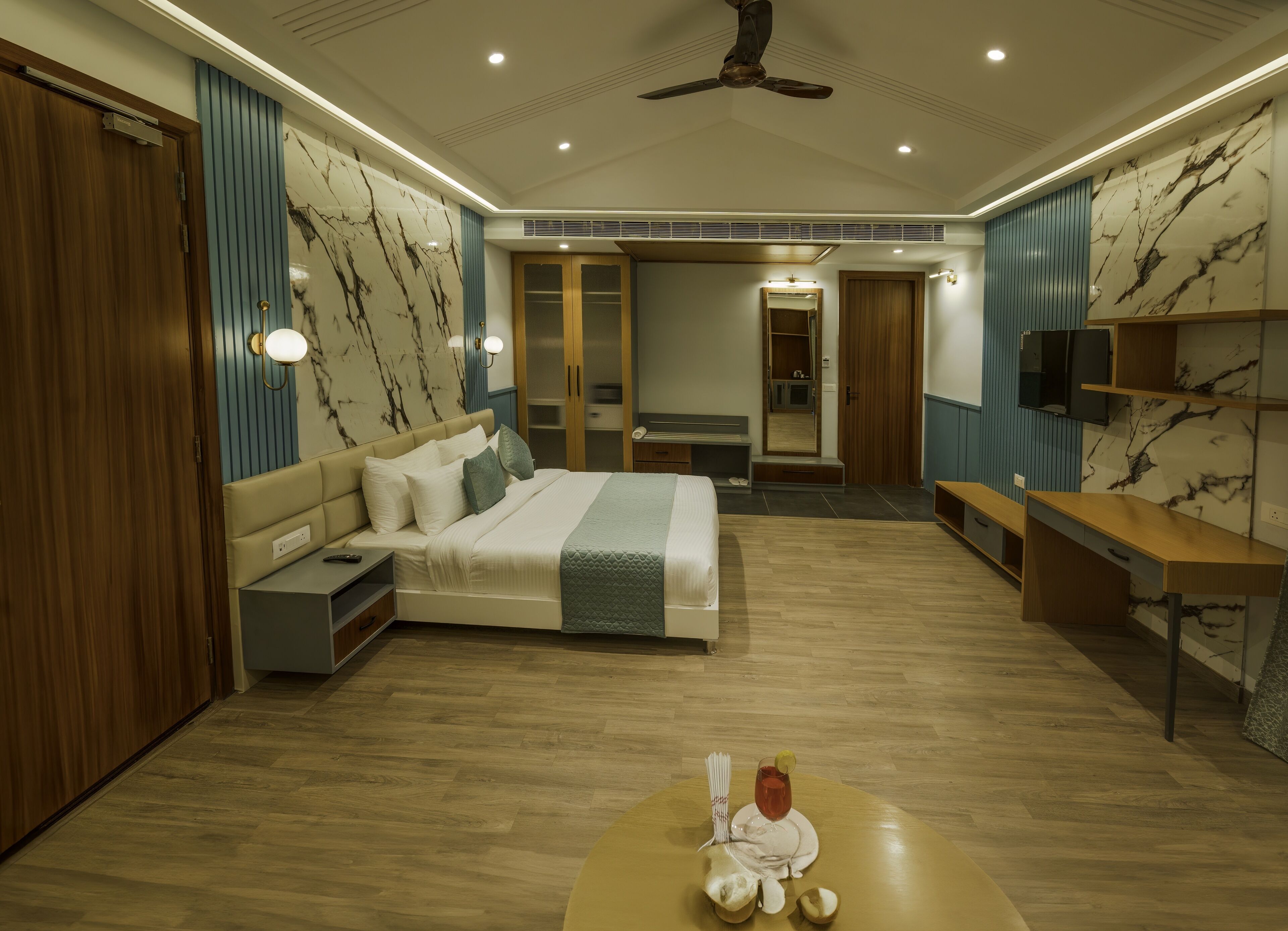 A modern hotel room with a large bed, a desk, a wardrobe, and a mirror.