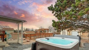 A hot tub in a backyard with a wooden deck, a covered patio, and a large tree. - Evergreen Luxe! Backyard Oasis w/ Pool & Hot Tub! (Colorado Springs)