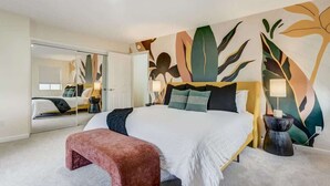 A modern hotel room with a large bed, a bench, a mirror, and a wall with abstract leaf patterns. - Evergreen Luxe! Backyard Oasis w/ Pool & Hot Tub! (Colorado Springs)