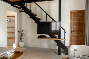 Stylish living area with a black staircase, wooden shelf, and a cozy sofa.