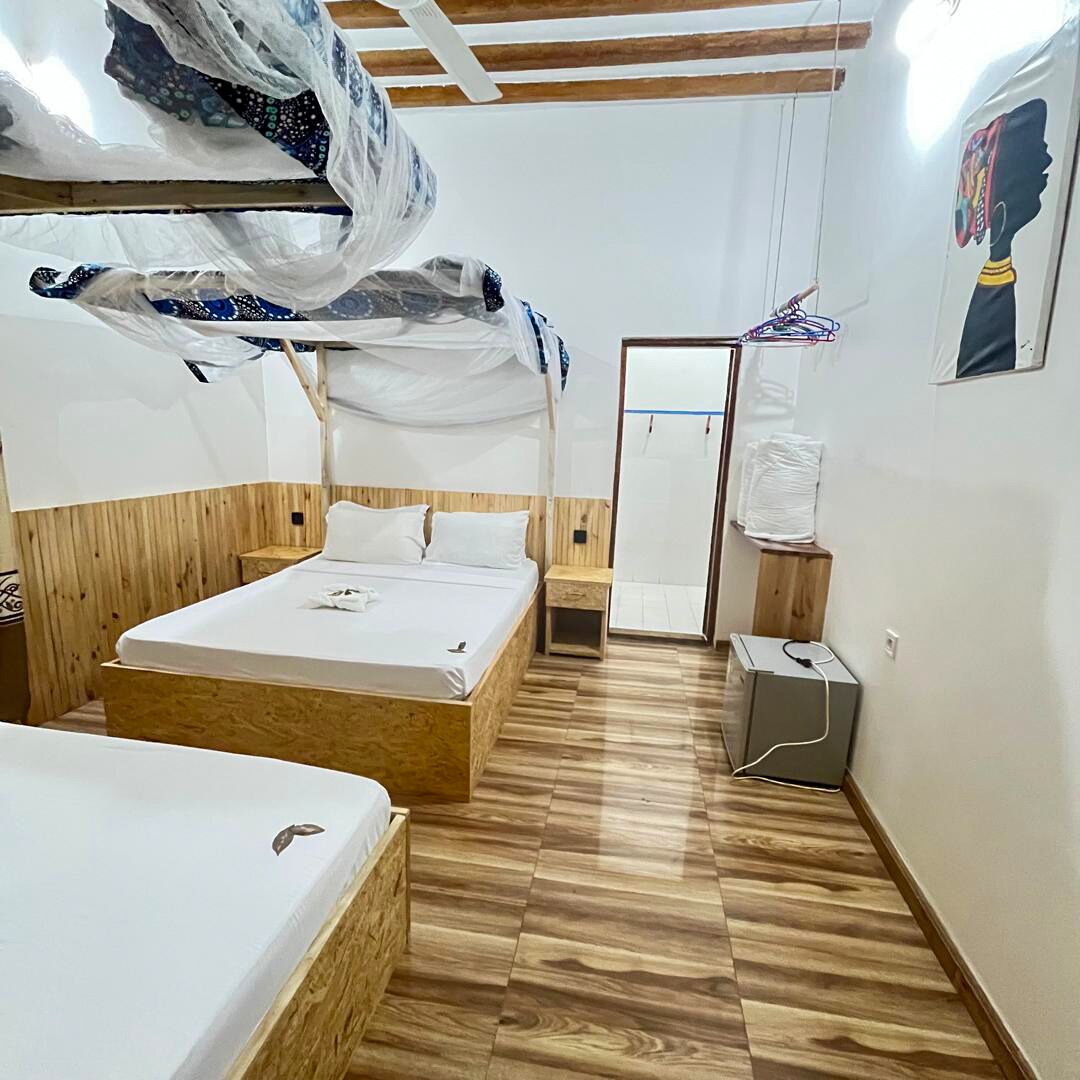 Una habitación con una cama de madera, una mesita de noche, un espejo y un aire acondicionado instalado en la pared.