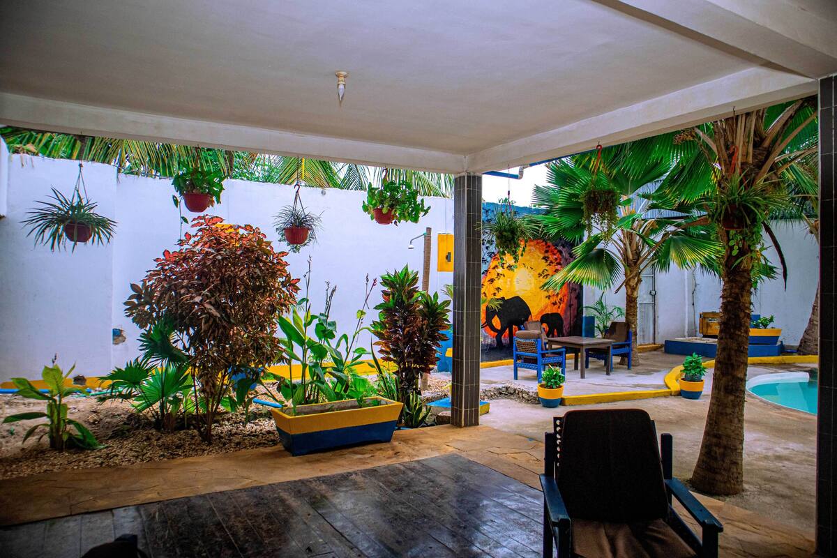 An indoor patio area with various potted plants, a pool, and seating arrangements.