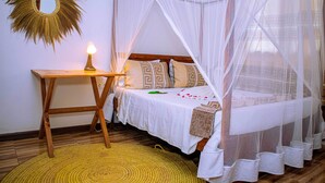 Un dormitorio con cama bajo un dosel, una mesita de noche con lámpara y un espejo decorativo en la pared.