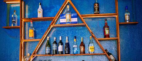 A display of various liquor bottles arranged on wooden shelves against a blue textured wall.