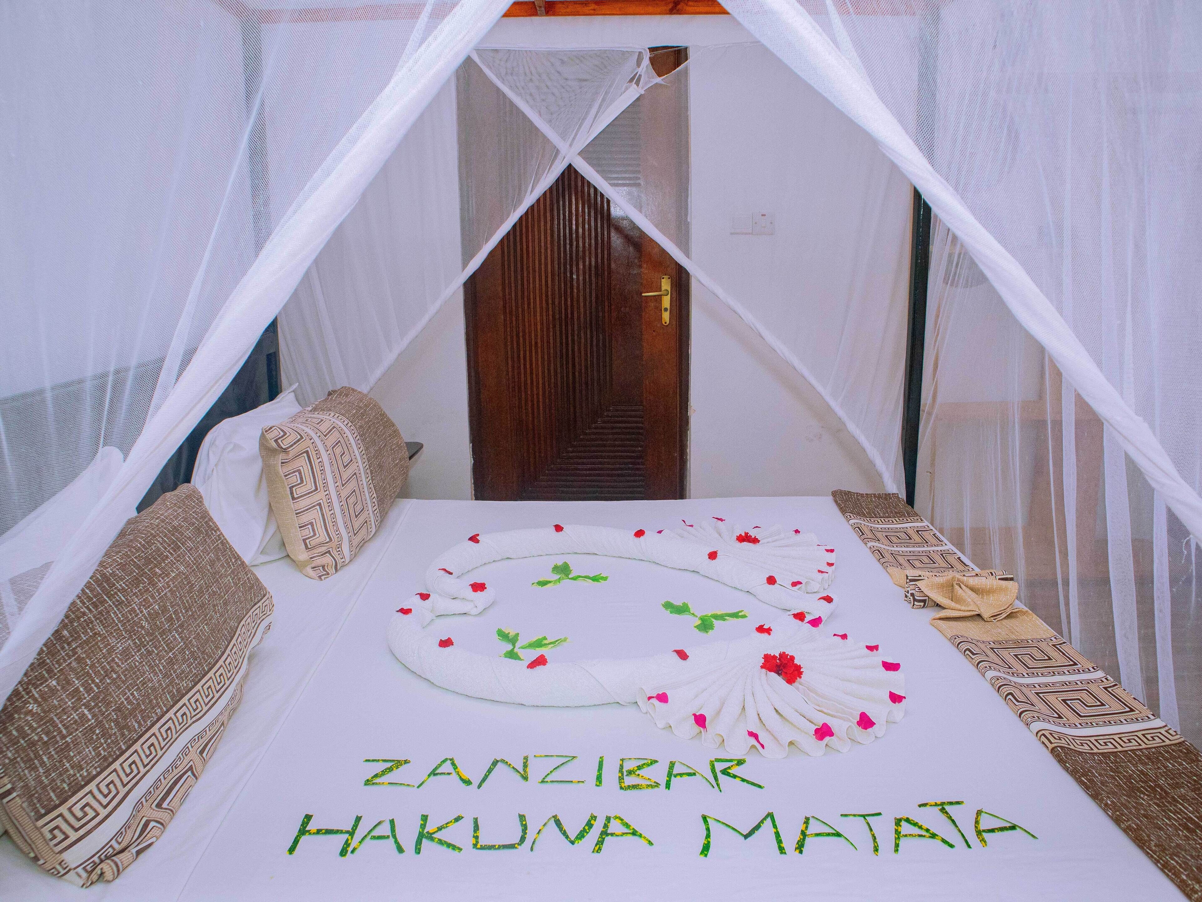 A bed with a canopy, pillows, and a decorative arrangement with flowers and text.