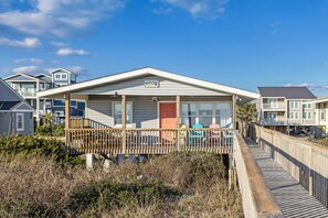 A beachfront house with a covered porch, a wooden deck, and a view of the ocean. - Amazing Dog Friendly Oceanfront 3 Bedroom Cottage, Steps to the Beach (Oak Island)