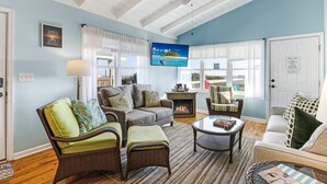 A living room with a fireplace, wicker furniture, and a television on the wall.