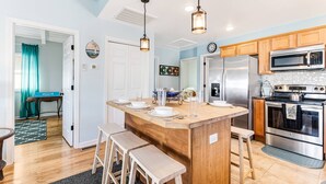 A kitchen with a wooden island, stainless steel appliances, and pendant lighting.