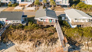 A beachfront property with multiple houses connected by a wooden deck.