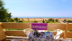 Ein Balkon mit Tisch für zwei Personen, mit Blick auf einen Strand.