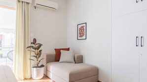 A bedroom with a bed, a potted plant, a framed picture on the wall, and a wardrobe.