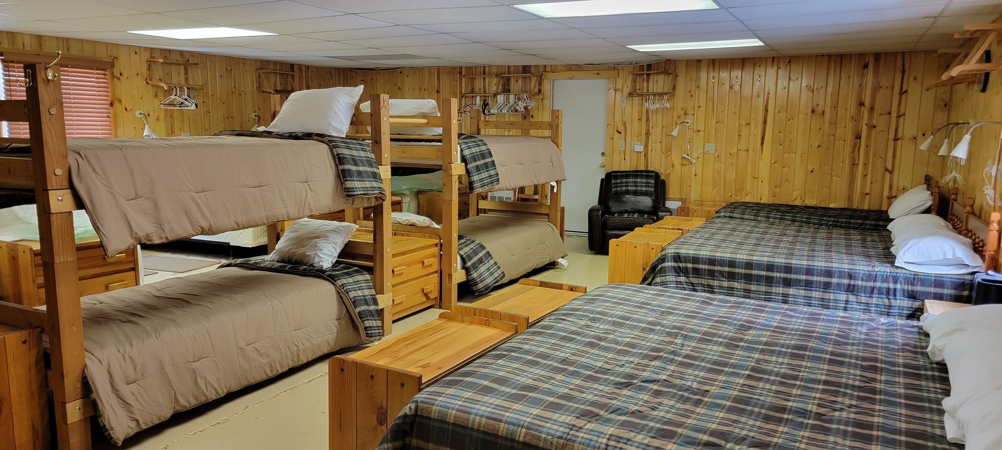 Quarto de dormitório com beliches, móveis de madeira e uma escrivaninha.