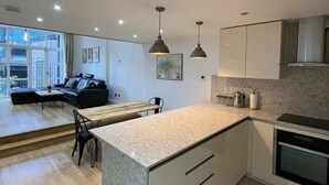 A modern kitchen with a marble countertop, integrated oven, and pendant lighting. - Stunning 3BD Maisonette W/balcony - Old Street! (London)