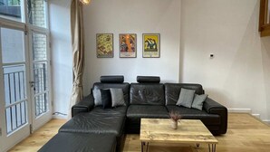 A modern living room with a sectional sofa, a coffee table, and a hanging light fixture. - Stunning 3BD Maisonette W/balcony - Old Street! (London)