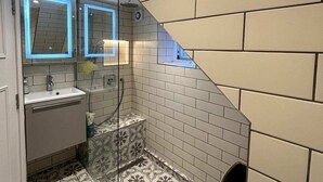 A bathroom with a white sink, a glass shower enclosure, and patterned floor tiles. - Elegant & Beautifully Presented 1BD Flat- Chelsea! (London)