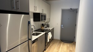 A modern kitchen with stainless steel appliances, white cabinets, and a wooden floor. - Chicago Shared Living Space with Office Space (Chicago)