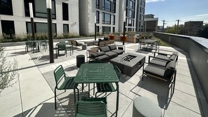 An outdoor patio with green metal furniture, a fire pit, and a barbecue area. - Chicago Shared Living Space with Office Space (Chicago)