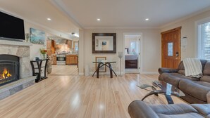Ein großzügiges Wohnzimmer mit Kamin, Essbereich und einer Küche im Hintergrund.