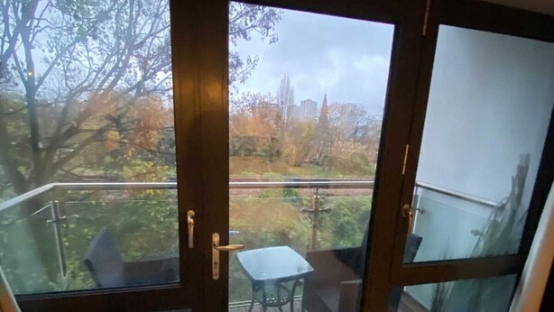 Una habitación con puerta de vidrio corrediza que da a un patio exterior con mesa y sillas.