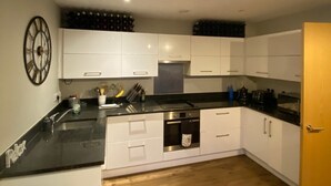 Una cocina moderna con armarios blancos, encimera negra y suelo de madera.