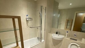 Un baño moderno con cabina de ducha de vidrio, bañera, lavabo e inodoro.