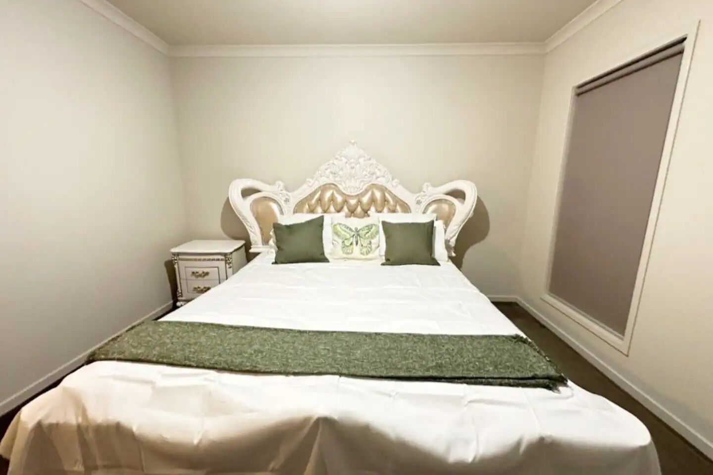 A neatly made bed with a white headboard and green bedding.