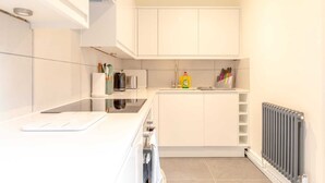 A modern kitchen with white cabinets, a black countertop, and a built-in stove. - Beautifully Presented 2BD Flat W/patio- Kensington (London)