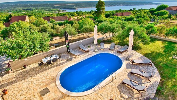 A swimming pool with lounge chairs and a stone deck, surrounded by greenery and overlooking a scenic landscape. - Villa with amazing sea view, quite area (Krusevo)