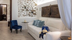 A room with a stone wall, a wooden door, a white sofa, a blue chair, and a small table with a lamp. - La Casa del 600 Sea View on the Amalfi Coast, with patio and garden (Tovere (San Pietro))