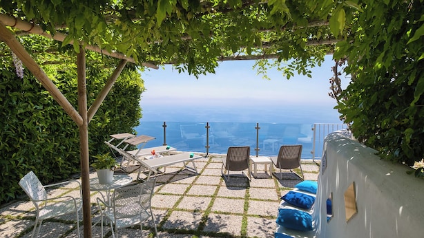 A terrace with a view, furnished with lounge chairs and a table, surrounded by greenery. - La Casa del 600 Sea View on the Amalfi Coast, with patio and garden (Tovere (San Pietro))
