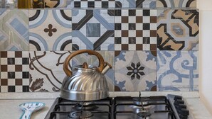 A kitchen with a gas stove, a kettle, and a backsplash with patterned tiles. - La Casa del 600 Sea View on the Amalfi Coast, with patio and garden (Tovere (San Pietro))