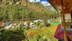 A mountainous landscape with a village and several buildings, including a prominent red-roofed structure. - Hotel Anupam  (Bhuntar)