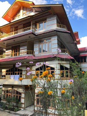 Un edificio de varios pisos con balcones y un jardín lleno de flores.