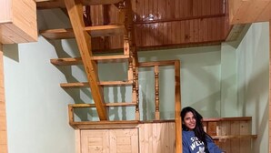 A wooden staircase in a room with light green walls and wooden flooring. - Hotel Anupam  (Bhuntar)