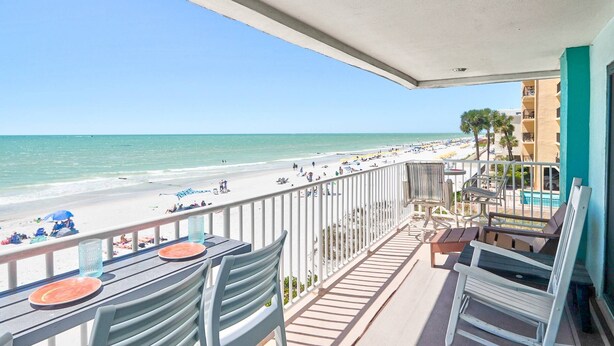 Un balcon avec vue sur la plage, un espace salon extérieur et une piscine.