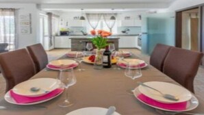 Un comedor con una larga mesa preparada para cuatro personas, rodeada de sillas marrones.