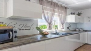 Una cocina moderna con armarios blancos, un microondas y un cuenco de fruta sobre la encimera.
