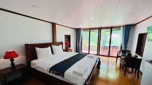 Un dormitorio amplio con una cama grande, un escritorio y vistas al exterior a través de una puerta corrediza de vidrio.