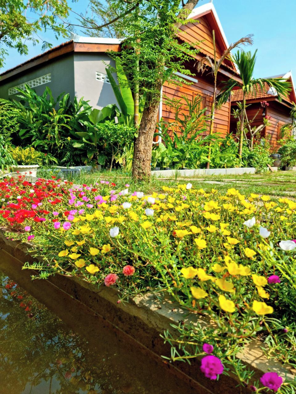 Een gebouw met een schuin dak en een tuin vol kleurrijke bloemen.