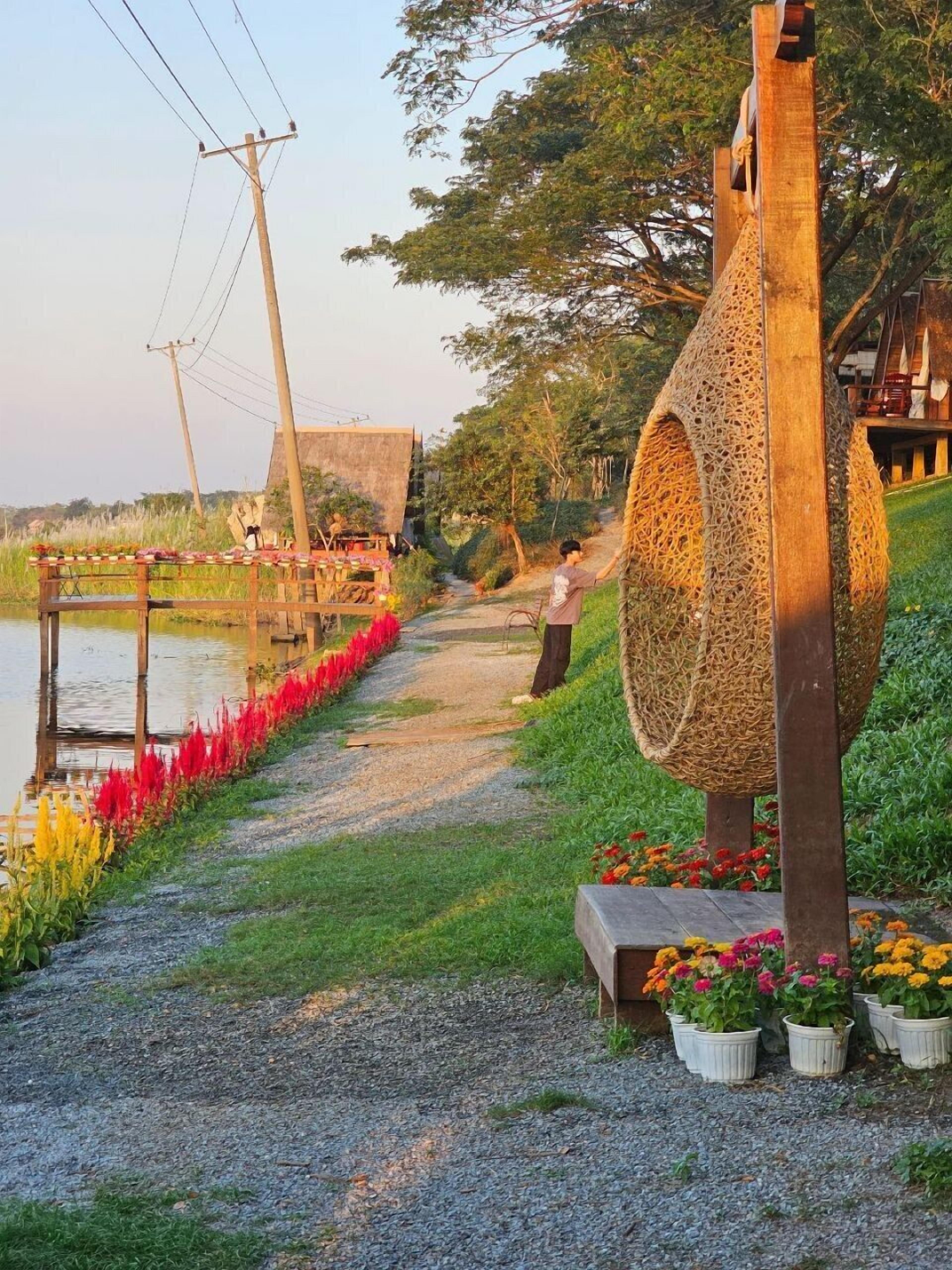 A pathway with a decorative structure, a small wooden building, and potted plants along the side.