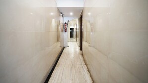 A corridor with marble flooring and walls, leading to a door at the end. - Hotel Twigo Inn (Mumbai)