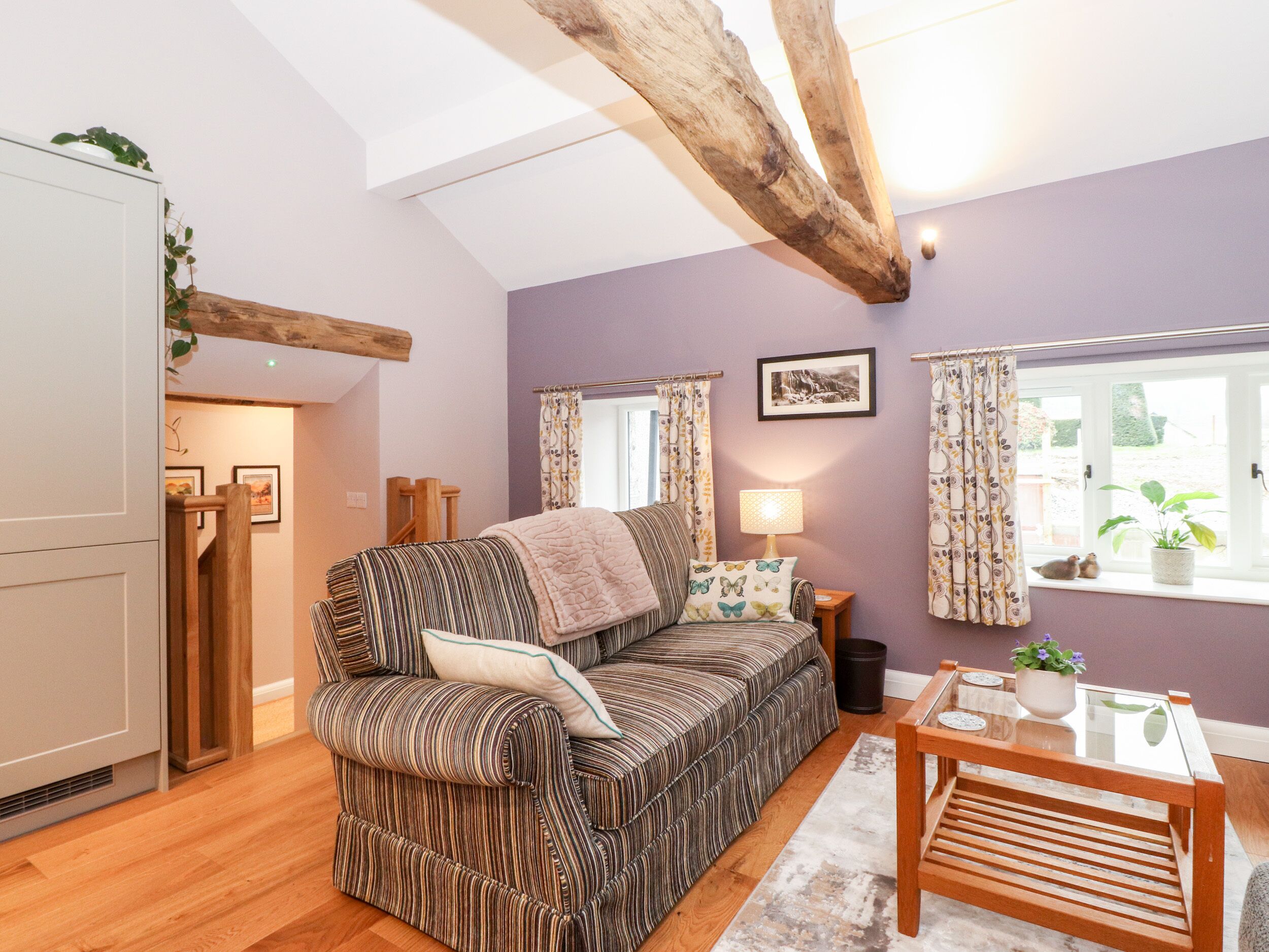 Una sala de estar acogedora con un sofá a rayas, una mesa de centro de madera y una ventana con cortinas.