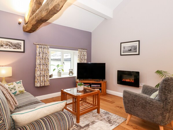 A living room with a sofa, a TV, a fireplace, and a window with curtains.