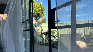 Une pièce dotée de grandes fenêtres en verre, d’une terrasse en bois et de mobilier d’extérieur.