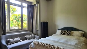 Une chambre à coucher avec un lit, un canapé et une fenêtre avec des rideaux.