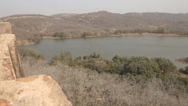 Un lac entouré de collines et d’une végétation clairsemée.