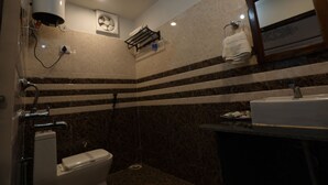 A bathroom with a toilet, sink, and mirror. There is a towel rack with a towel hanging on it. The walls have a striped pattern. - Hem Vilas (Sawai Madhopur)