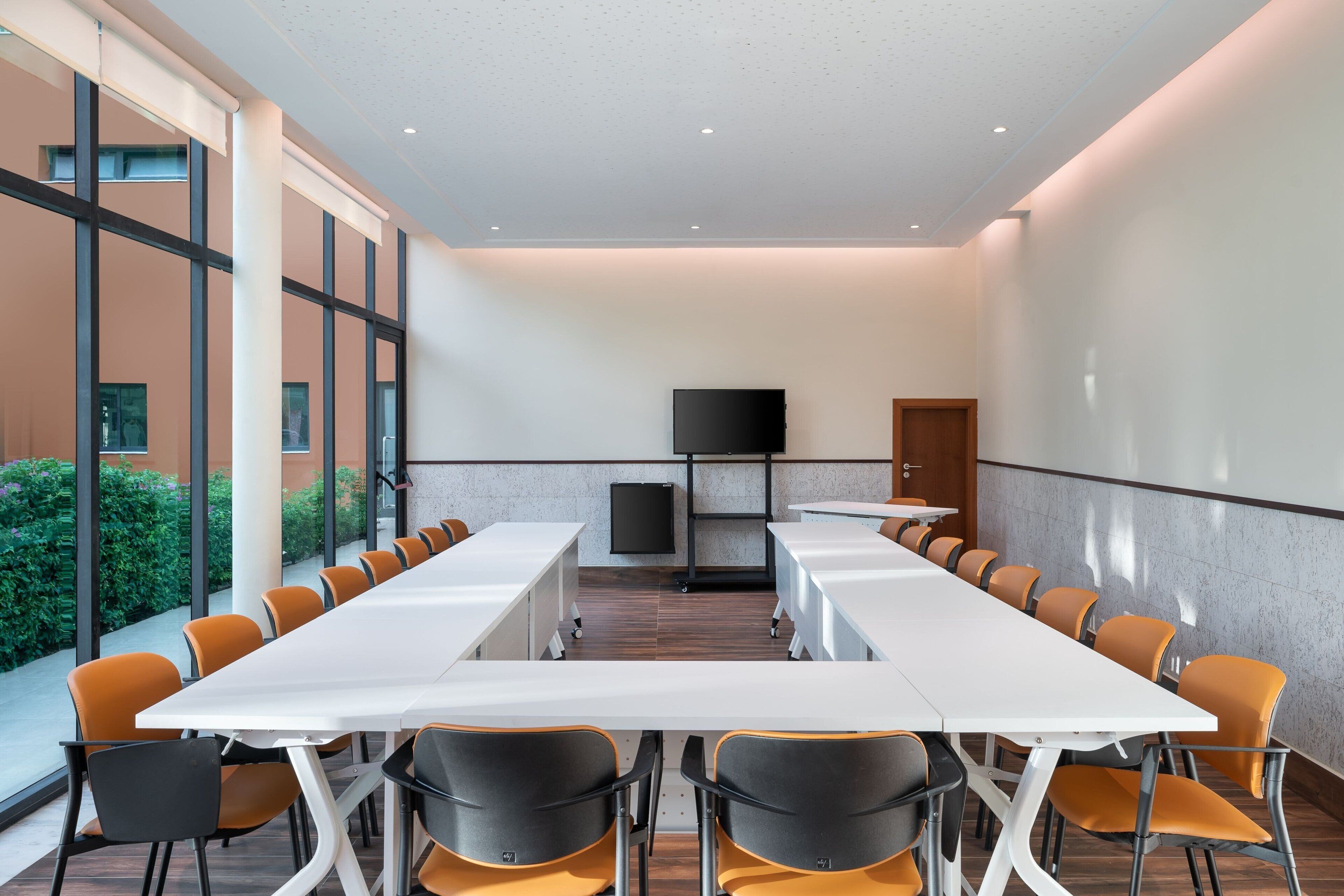 A conference room with a long table, chairs, a TV, and a door.