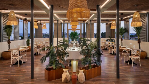 A spacious dining area with high ceilings, modern pendant lighting, and a view of the cityscape. - Protea Hotel Luanda (Luanda)