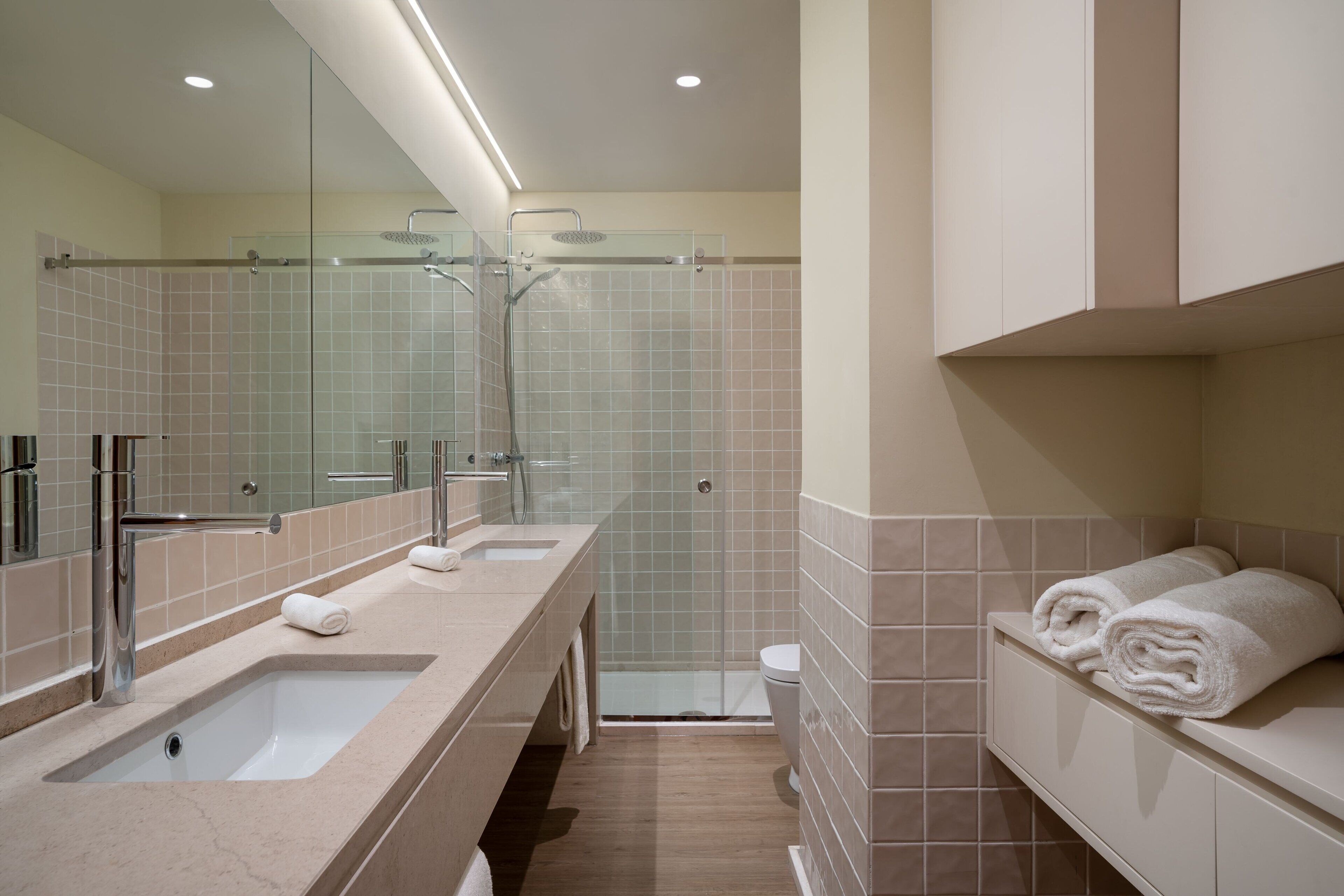 Un baño moderno con un lavamanos grande, cabina de ducha con mampara de vidrio y un perchero para toallas.